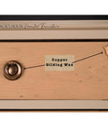 A wooden drawer shows a round metal handle and keyhole. Text labels point to these features: “Copper Gilding Wax” is indicated between the handle and keyhole. The drawer is part of Gracie’s House Painted Furniture collection.