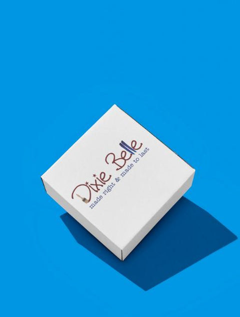 A white square box with the words â€œDixie Belle made right &amp; made to lastâ€ in script font, placed on a bright blue background with a shadow extending to the right.