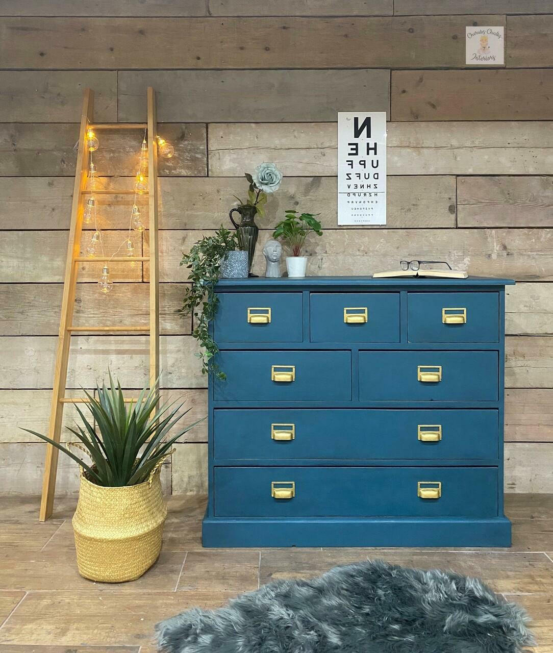 Dixie Belle Paint Antebellum Blue Chalk Mineral Paint is the perfect paint for any DIY project! Antebellum Blue Chalk Mineral Paint on dresser with gold hardware. Staged with books, reading glasses, plants and ladder light.