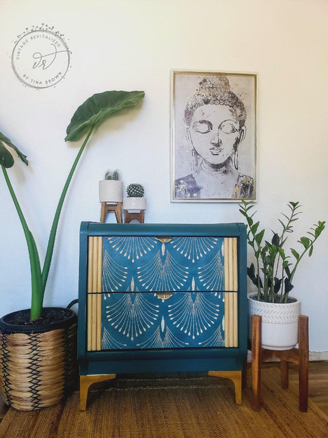 Dixie Belle Paint Antebellum Blue Chalk Mineral Paint is the perfect paint for any DIY project! Small dresser with gold stencil over Antebellum Blue Chalk Mineral Paint. The piece is staged with various style planters and portrait against white wall.