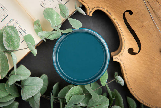 Dixie Belle Paint Antebellum Blue Chalk Mineral Paint is the perfect paint for any DIY project! Open container of Antebellum Blue Chalk Mineral Paint against black background with cello and music sheet.