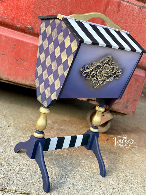 Dixie Belle Paint Aubergine Chalk Mineral Paint is the perfect paint for any DIY project! Ths vintage magazone rack is painted with several Dixie Belle Chalk Mineral Paint colors including Aubergine Chalk Mineral Paint. It is ebelished on the sides using Dixie Belles Harlequin Stencils and a WoodUBend design accents the front.