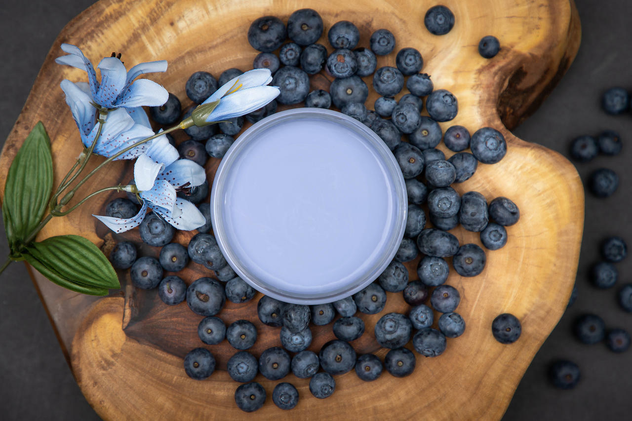 Dixie Belle Paint Blueberry Chalk Mineral Paint is the perfect paint for any DIY project!
Aerial view of opened container of Blueberry Chalk Mineral Paint staged on top of wooden circular board with blueberries and flower around container.