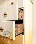 Dixie Belle Paint Buttercream Chalk Mineral Paint is the perfect paint for any DIY project!
Opened drawer of a dresser in Buttercream Chalk Mineral Paint fading into a mute yellow with the side of the drawers showing Sunflowers - Transfer.