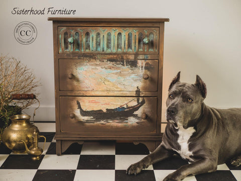 Dixie Belle Paint Chocolate Chalk Mineral Paint is the perfect paint for any DIY project. Chocolate Chalk Mineral Paint dresser with a faded circle on the 2nd and 3rd drawer inside faded circle is Gondola and Landscape - A1 Rice Decoupage Paper faded. Mint paint stippled on top drawer with mint hardware  on top drawer. Staged on black and white checkered floor with large gray and white chest pitbull on the right of furniture with different sized gold pitcher and bucket on the left.