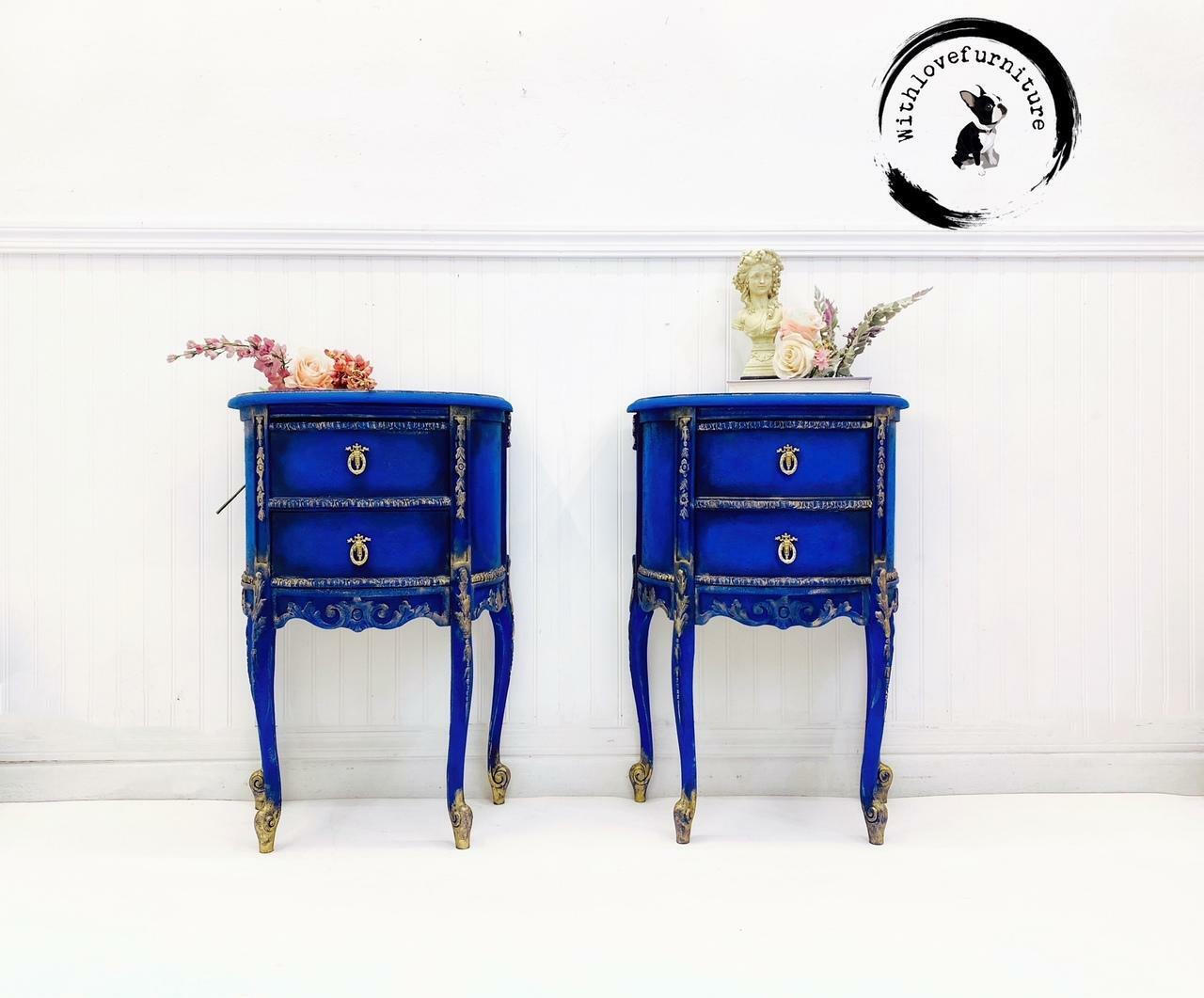 Dixie Belle Paint Cobalt Blue Chalk Mineral Paint is the perfect paint for any DIY project!
There are two side tables next to each other both painted with Cobalt Blue CMP.  They both have two draws and have Wood-U-Bend trim painted gold.  On top of the side table on the left has pretty dried flowers with colors of pink, peach and rose.  On the side table on the right there are dried flowers of Pink and green with a white statue of a little girl.