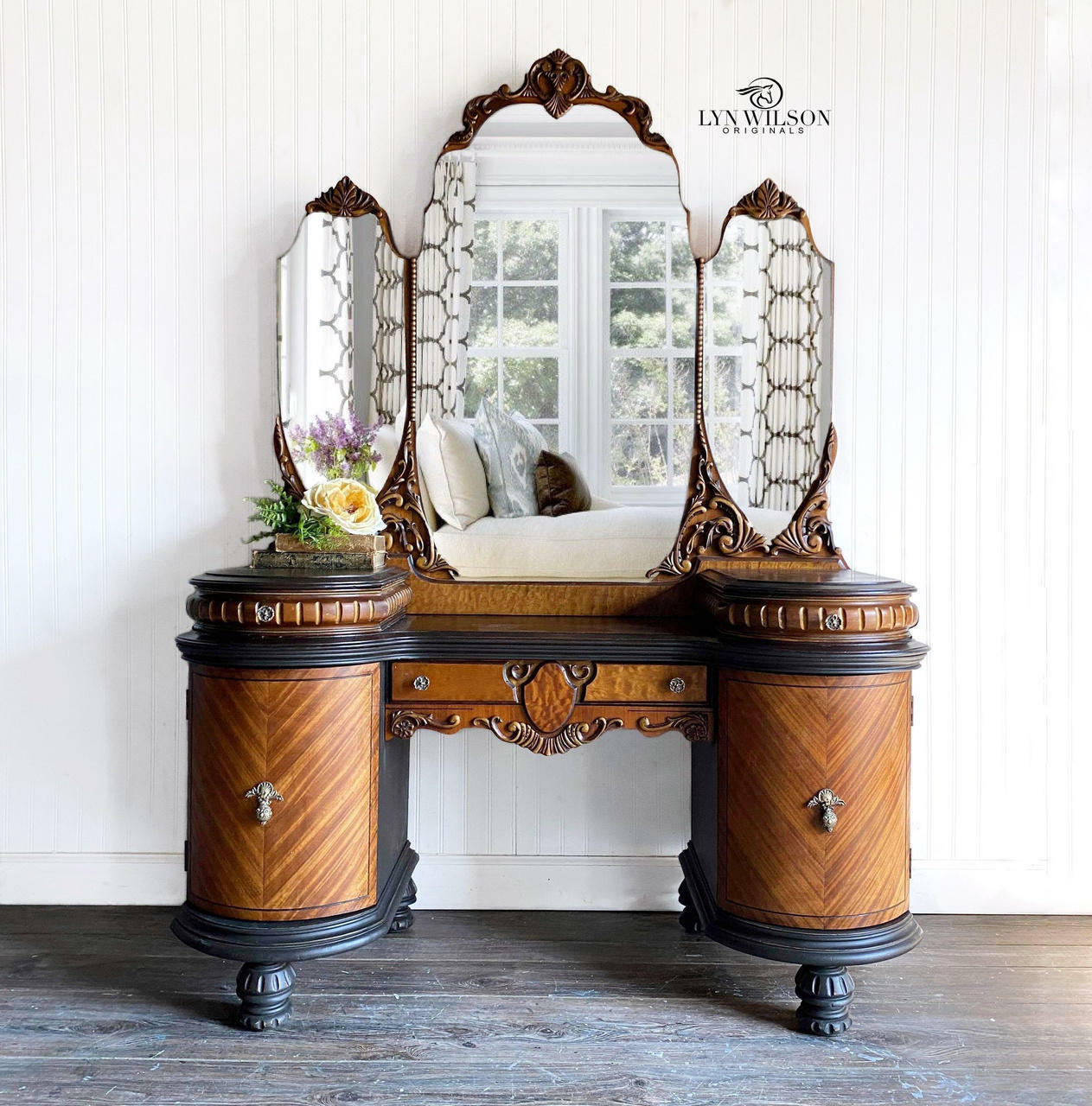 Dixie Belle Paint Coffee Bean Chalk Mineral Paint is the perfect paint for any DIY project!
There is an ornate desk trimmed in Coffee Bean CMP.  Most of the desk is left with the natural wood grain exposed. On top of the desk is a large mirror with 3 sides. The middle mirror is larger than the two that flank the larger, middle mirror.  on top of the desk is a large, white flower rest on fern.  There is a Dixie Belle Paint Company Content Creator watermark in the upper right corner of the picture.