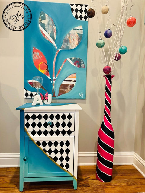 Dixie Belle Paint Cotton Chalk Mineral Paint is the perfect paint for any DIY project! A small end table with a gold strip across the center of the piece separating a blended blue look on the bottom half and a white and black diamond pattern look on the right top half and is staged with a matching painting and some home decor.