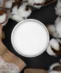 Dixie Belle Paint Cotton Chalk Mineral Paint is the perfect paint for any DIY project!
In this picture you look directly down on the can of cotton CMP.  It rests on a black, matte surface.  Coming in from the right side of the picture are branches of real cotton.  All the cotton is bursting out of their pods.  on the left of the paint and going all the way to the edge of the picture is a burlap fabric with white lace over the top.