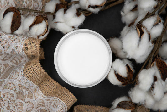 Dixie Belle Paint Cotton Chalk Mineral Paint is the perfect paint for any DIY project!
In this picture you look directly down on the can of cotton CMP.  It rests on a black, matte surface.  Coming in from the right side of the picture are branches of real cotton.  All the cotton is bursting out of their pods.  on the left of the paint and going all the way to the edge of the picture is a burlap fabric with white lace over the top.