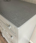 Dixie Belle Paint Crackle. A closeup of a white dresser with a gray top displaying the crackle effect on the top.