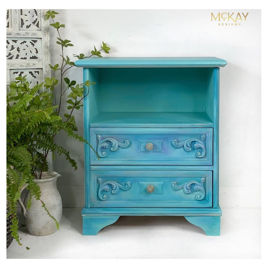 Dixie Belle Paint Dixie Belle Blue Chalk Mineral Paint is the perfect paint for any DIY project!
This is a side table for a bedroom.  There  is an open area on top and two drawers on the bottom.  It  is painted in Dixie Belle Blue CMP.  It is staged with plants and a china wall.