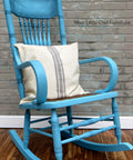 Dixie Belle Paint Dixie Belle Blue Chalk Mineral Paint is the perfect paint for any DIY project!
This is an old fashioned rocking chair painted in Dixie Belle Blue CMP.  There is a cream pillow on the seat of the rocker and the pillow has 3 stipes of brown color.  The chair is in front of a brick wall and rests on a glossy, wood floor.