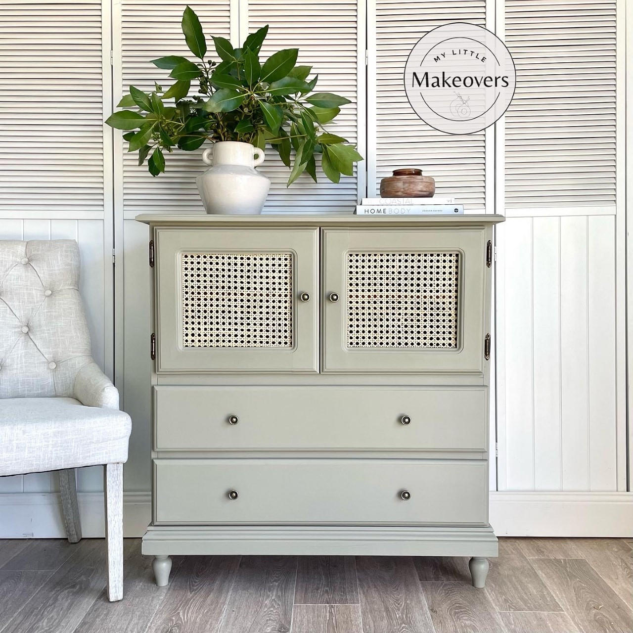 Dixie Belle Paint Dried Sage Chalk Mineral Paint is the perfect paint for any DIY project!
Cabinet with cane webbing doors above drawers painted in Dried Sage Chalk Mineral Paint. Staged on wood floors and a white door panel background. On top has a white vase with handles and greenery.