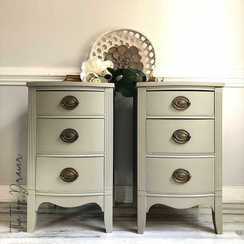 Dixie Belle Paint Dried Sage Chalk Mineral Paint is the perfect paint for any DIY project!
Two bedside tables with bronze hardware painted in Dried Sage Chalk Mineral Paint. Staged with a bronze flower and greenery on top of tables.