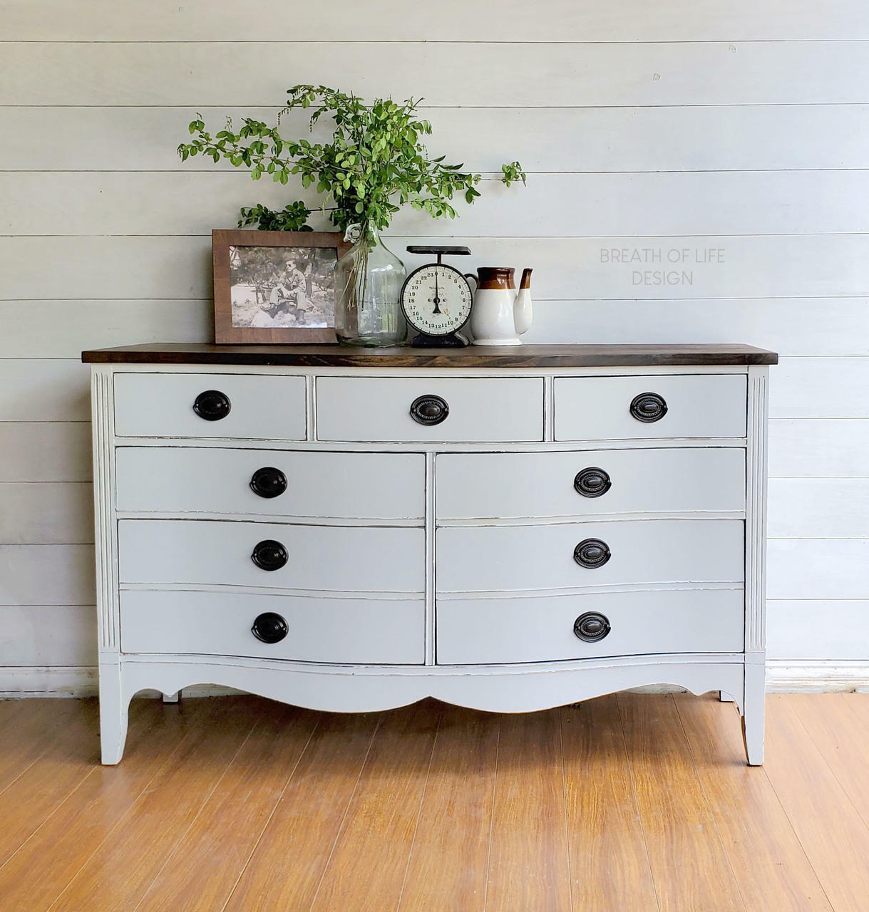 Dixie Belle Paint Driftwood Chalk Mineral Paint is the perfect paint for any DIY project!
Gray chalk painted dresser with stained wood top and black handles. Staged with a photo, clock, vase with greenery and a tea pot.