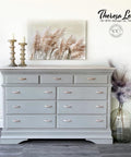 Dixie Belle Paint Driftwood Chalk Mineral Paint is the perfect paint for any DIY project!
Gray chalk painted dresser makeover with silver handles. Staged with candle sticks, a picture of cattails blowing in the wind, and a vase full of feathers.