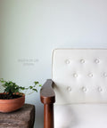 Dixie Belle Paint Drop Cloth Chalk Mineral Paint is the perfect paint for any DIY project! White chalk painted chair with a wooden arm. Staged next to a wooden table with a clay pot containing a pothos plant on top.