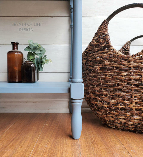 Dixie Belle Paint Dusty Blue Chalk Mineral Paint is the perfect paint for any DIY project! Blue chalk painted furniture makeover. Staged with small glass vases with greenery and a large woven basket next to the furniture on a wooden floor.