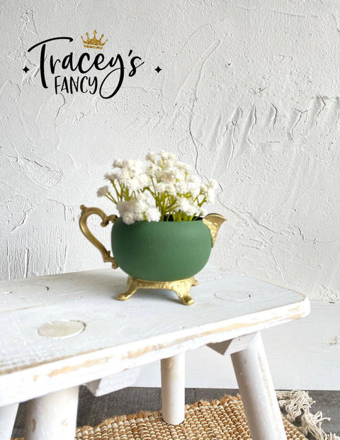 Green chalk painted pitcher with gold legs, handle and spout. Staged on a white painted distressed stool.