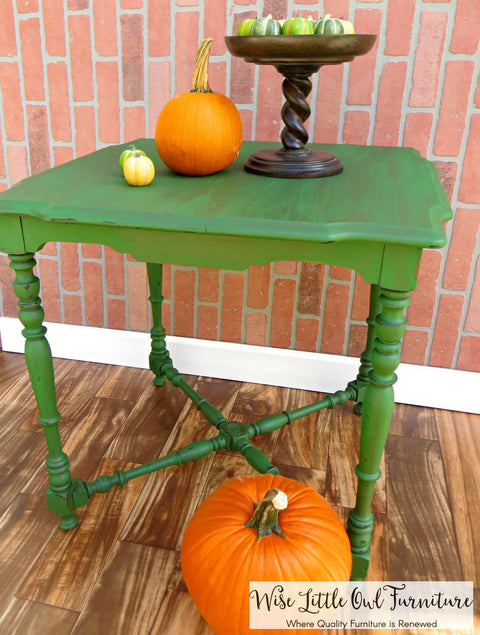 Dixie Belle Paint Evergreen Chalk Mineral Paint is the perfect paint for any DIY project! Green painted table with a dark wash. Two very small and one medium pumpkins on top next to a brown cake stand holding more small pumpkins. One large pumpkin placed underneath the table.