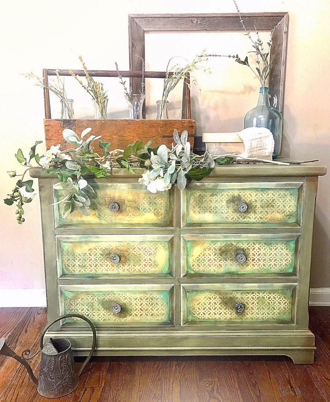 Dixie Belle Paint Farmhouse Green Chalk Mineral Paint is the perfect paint for any DIY project!
A dresser with the body painted in Farmhouse Green Chalk Mineral Paint with the drawers yellow distressed with a star pattern. Staged with flowers,greenery and glass vases.