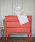 Dixie Belle Paint Flamingo Chalk Mineral Paint is the perfect paint for any DIY project!
Dresser painted in Flamingo Chalk Mineral Paint with crystal hardware, staged with white dishes and pots on top of the piece.