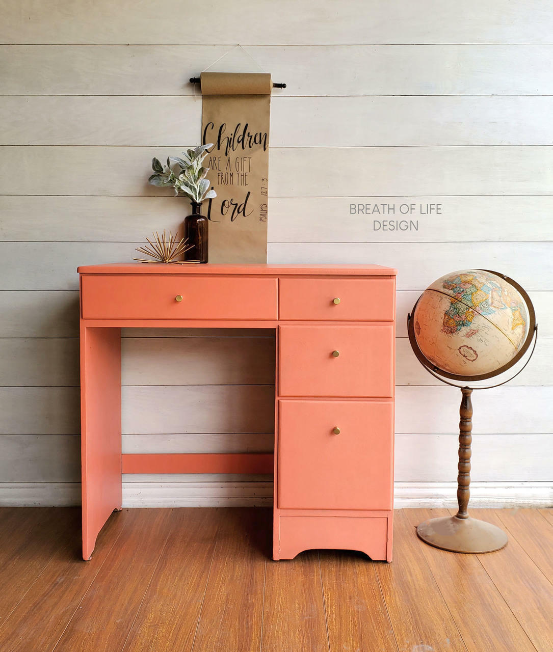 Dixie Belle Paint Flamingo Chalk Mineral Paint is the perfect paint for any DIY project!
Single pedestal desk painted in Flamingo Chalk Mineral Paint with gold hardware. A Globe is standing next to the left side of the desk, a brown glass bottle with greenery.