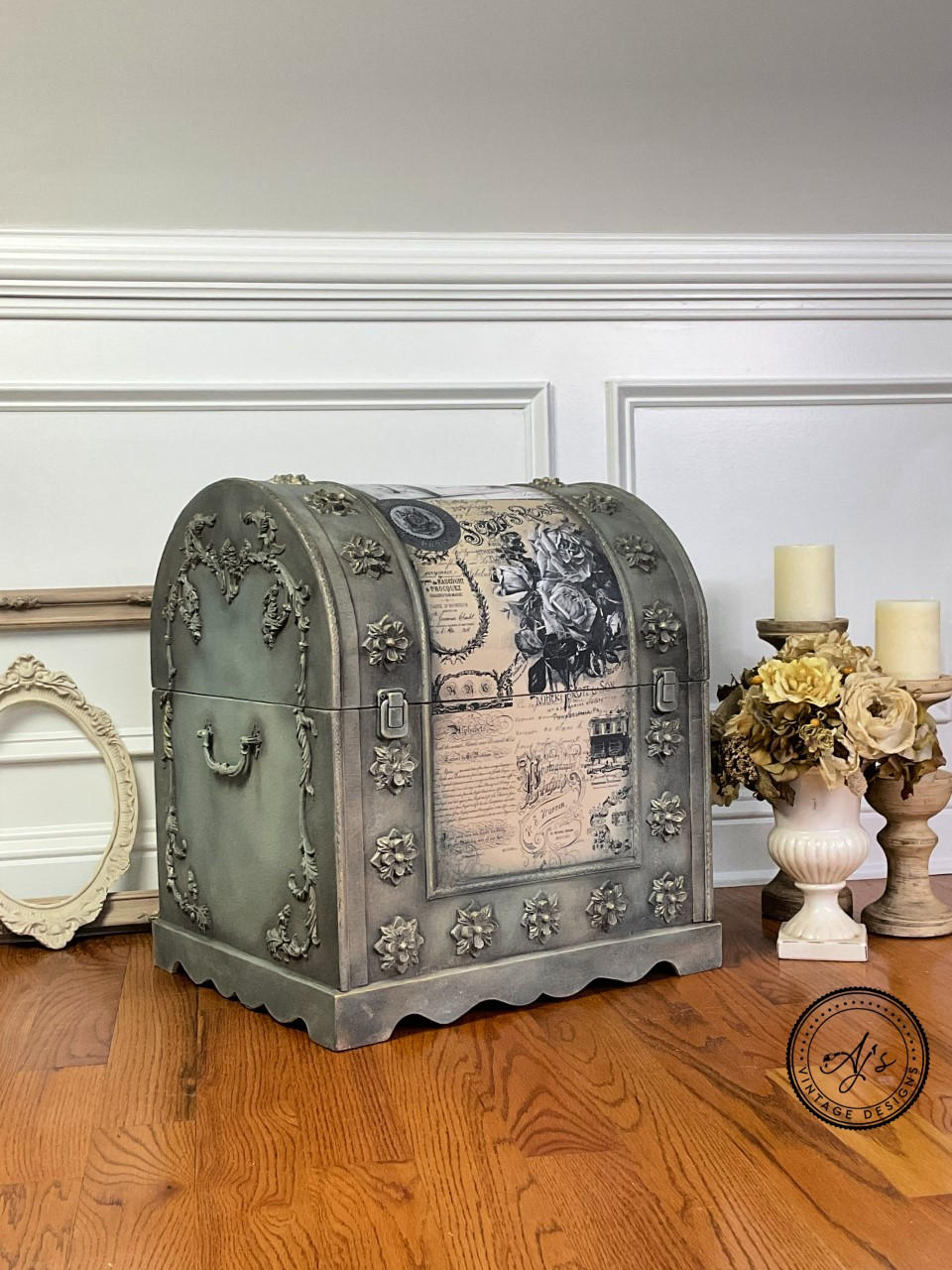 Dixie Belle Paint Gravel Road Chalk Mineral Paint is the perfect paint for any DIY project! Small vintage chest painted in Gravel Road Chalk Mineral Paint with Belles & Whistles Vintage Post - Transfer down the center. Stage on laminated wood flooring with 2 different sized candle holder on the right to the piece Infront of them is a white planter with neutral colored flowers.