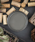 Dixie Belle Paint Gravel Road Chalk Mineral Paint is the perfect paint for any DIY project! Top view of open container of Gravel Road Chalk Mineral Paint. Staged with corks, artichokes, pinecone and driftwood.