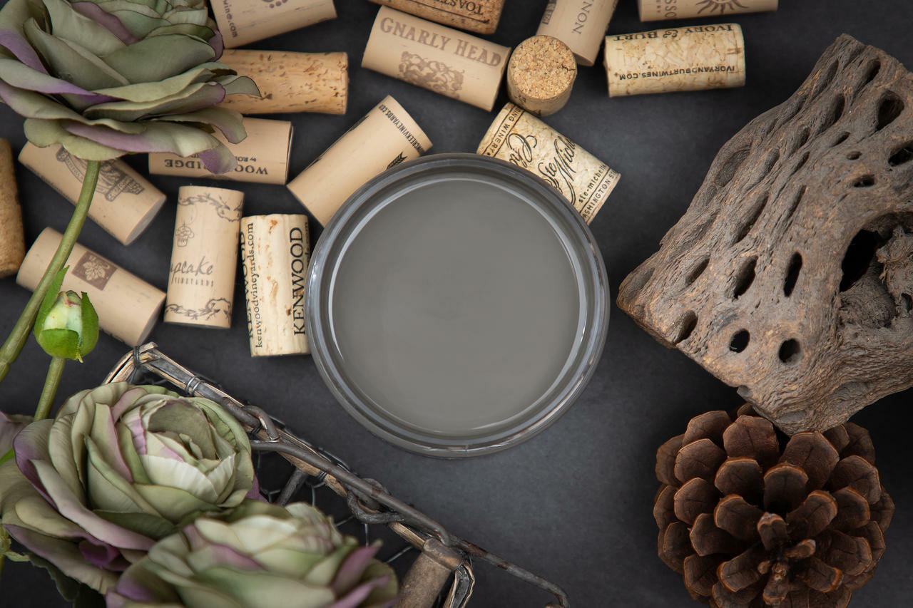 Dixie Belle Paint Gravel Road Chalk Mineral Paint is the perfect paint for any DIY project! Top view of open container of Gravel Road Chalk Mineral Paint. Staged with corks, artichokes, pinecone and driftwood.
