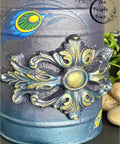 Dixie Belle Paint Hi Ho Silver Glaze
a close up image of a vintage milk can painted in a blend of Chalk Mineral Paint in Aubergine, Antebellum Blue, Peacock with the WoodUbend  applique in 1339 using the Hi Ho Silver Glaze on the edges on applique.