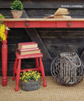 Dixie Belle Paint Honky Tonk Red Chalk Mineral Paint is the perfect paint for any DIY project!
A table with a light wood top and bench both painted in Honky Tonk Red Chalk Mineral Paint staged with yellow flowers and greenery as well as books are seen around and on both pieces of furniture. Staged on a brown rug and a rustic wood background.