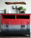 Dixie Belle Paint Honky Tonk Red Chalk Mineral Paint is the perfect paint for any DIY project!
A credenza with gradient effect with the starting color Honky Tonk Red Chalk Mineral Paint fading into gray then black with black hardware. Staged on top of the piece are potted houseplants and vases with a sign above the piece that reads "HELLO".