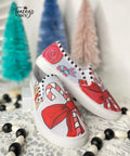 Dixie Belle Paint Honky Tonk Red Chalk Mineral Paint is the perfect paint for any DIY project!
Image shows a pair of slip on sneakers that have candy canes and bows all using the Honky Tonk Red Chalk Mineral Paint. Staged with black and white beads around the sneakers with three miniature Christmas trees in the background.