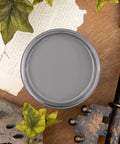 Dixie Belle Paint Hurricane Gray Chalk Mineral Paint is the perfect paint for any DIY project!
Top view of an opened container of  Hurricane Gray Chalk Mineral Paint staged with greenery, large antique key, driftwood, and ripped paper around the piece.