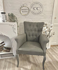 Dixie Belle Paint Hurricane Gray Chalk Mineral Paint is the perfect paint for any DIY project!
A Fabric cushion chair painted in Hurricane Gray Chalk Mineral Paint  staged next to a white fireplace in front of a white brick wall on top of a wooden floor.