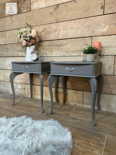Dixie Belle Paint Hurricane Gray Chalk Mineral Paint is the perfect paint for any DIY project!
Two end tables painted in  Hurricane Gray Chalk Mineral Paint with silver hardware and flowers inside vases with an alarm clock to the right of it is seen on top of the pieces.