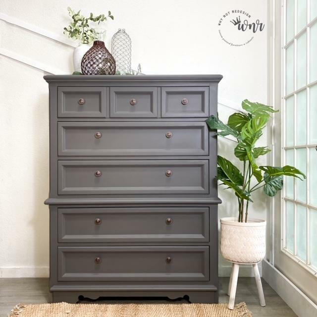 Dixie Belle Paint Hurricane Gray Chalk Mineral Paint is the perfect paint for any DIY project!
Chest of drawers painted in Hurricane Gray Chalk Mineral Paint with bronze hardware,staged with 3 different vases on the top of the piece as well as a standing potted houseplant to the right.