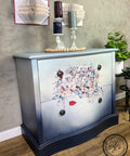Dixie Belle Paint In the Navy Chalk Mineral Paint is the perfect paint for any DIY project!
a 2 drawer dresser with an ombre effect painted with the following colors; In The Navy CMP,French Linen CMP,Drop Cloth CMP,Savannah Mist CMP,Apricot CMP. As well as the Bohemian Wedding - Transfer on the center of the dresser.  Staged with white candle pedestal with a red,green,blue candle on each on top of the piece.