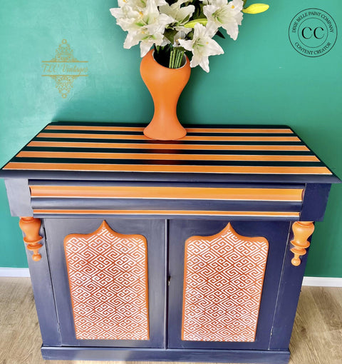 Dixie Belle Paint In the Navy Chalk Mineral Paint is the perfect paint for any DIY project!
A Drink cabinet painted with In the Navy Chalk Mineral Paint along with orange stripes and the Greek Key - Stencil on the door panel.