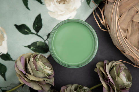 Dixie Belle Paint Kudzu Chalk Mineral Paint is the perfect paint for any DIY project!
Top view of an opened container of Kudzu Chalk Mineral Paint staged with red & purple roses, wooden basket and on top of a white rose pattern cloth.