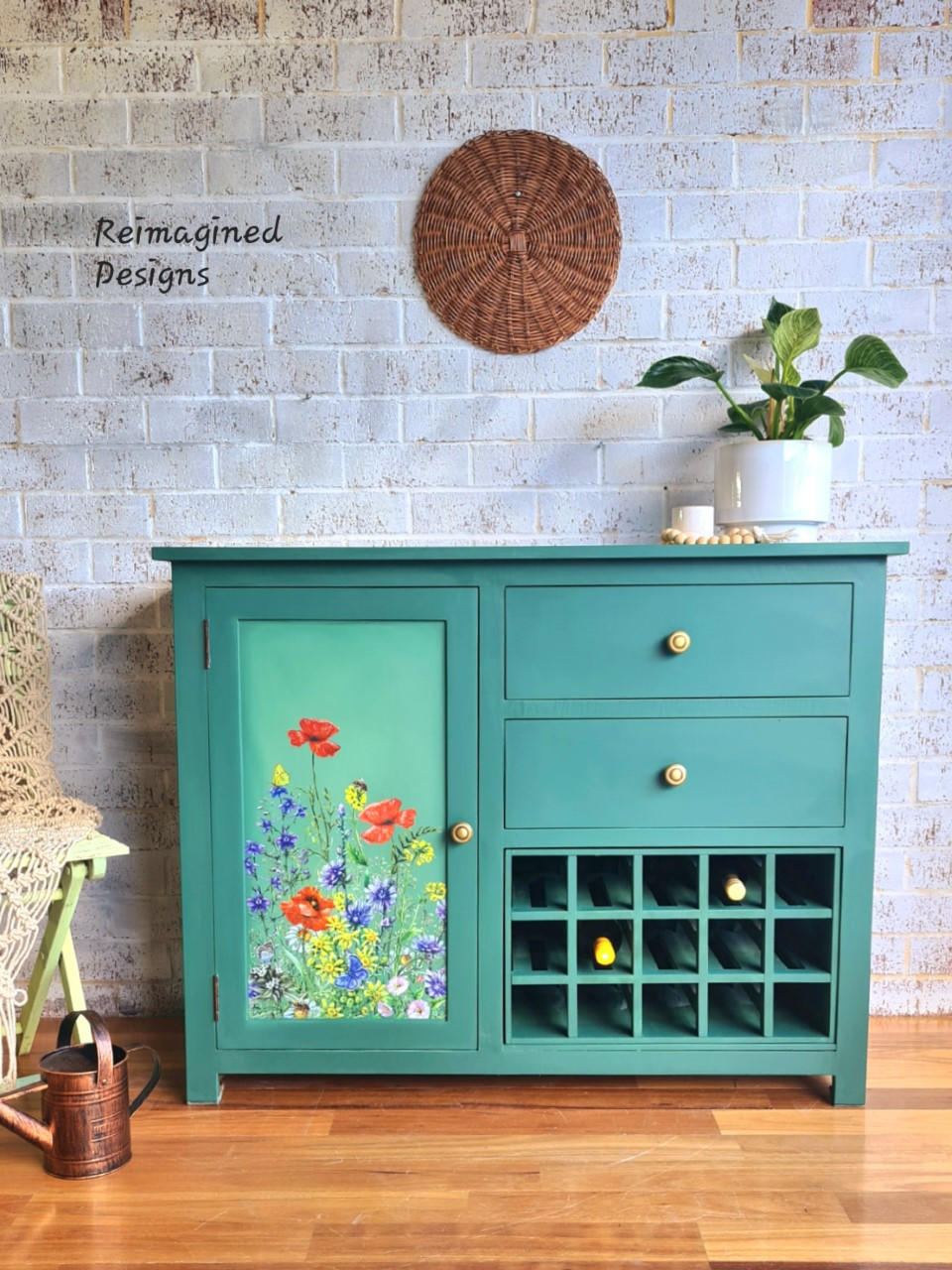 Dixie Belle Paint Kudzu Chalk Mineral Paint is the perfect paint for any DIY project!
A bar piece is painted in Kudzu Chalk Mineral Paint with gold hardware and on the door panel is the transfer Wildflowers & Butterflies. Staged with a white pot and a white candle with wooden beads on top of the piece.