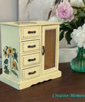 Dixie Belle Paint Lemonade Chalk Mineral Paint is the perfect paint for any DIY project!
Jewelry box painted with black hardware and the Sunflower Transfer is seen on the top of the piece and on the side panel as well. Staged besides a glass vase of white and pink flowers on a brown wood platform.