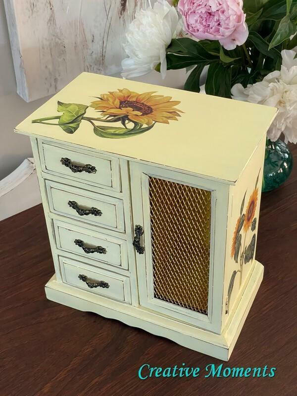 Dixie Belle Paint Lemonade Chalk Mineral Paint is the perfect paint for any DIY project!
project!
Jewelry box painted with black hardware and the Sunflowers Transfer is seen on the top of the piece and on the side panel as well. Staged besides a glass vase of white and pink flowers on a brown wood platform.