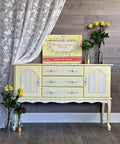 Dixie Belle Paint Lemonade Chalk Mineral Paint is the perfect paint for any DIY project!
Credenza painted in Lemonade Chalk Mineral Paint with gray stripes on the door panels and trim. along with white hardware, staged with glass bottles and yellow/red roses inside them.