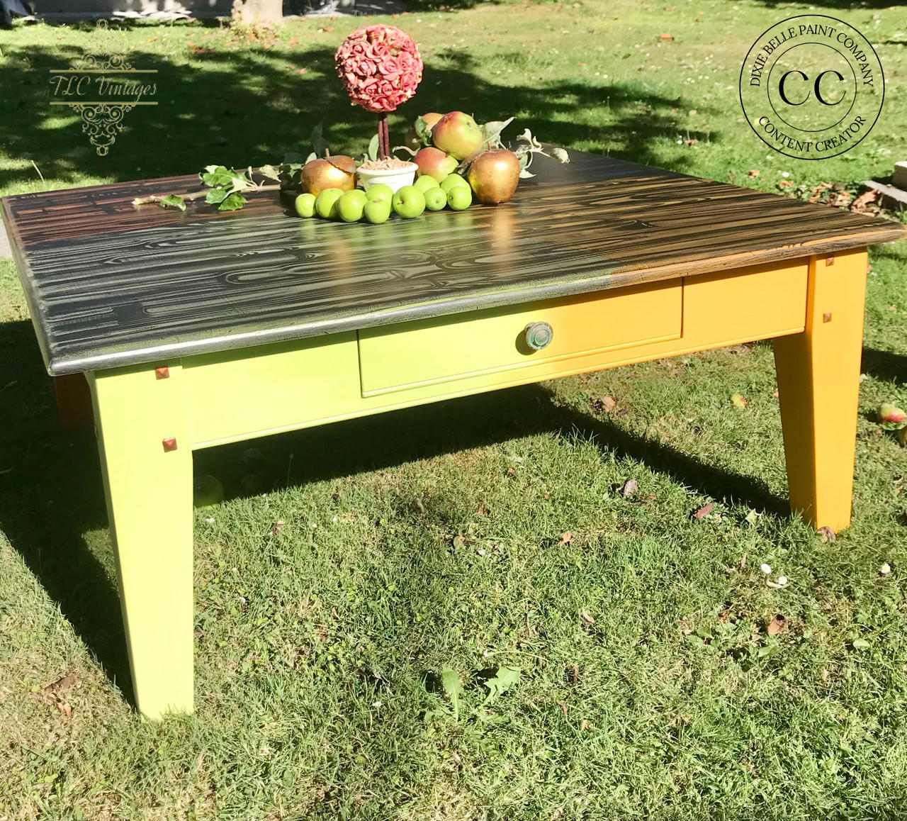 Dixie Belle Paint Limeade Chalk Mineral Paint is the perfect paint for any DIY project!
A coffee table painted half with Limeade and the other with Florida Orange with a Patina copper paint and Green Patina Spray hardware. Staged outside on grass,  green apples and red apple are seen on top of the piece.