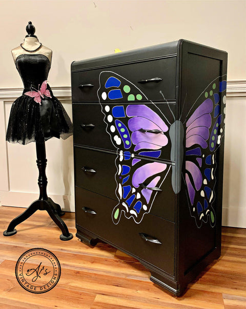 Dixie Belle Paint Lucky Lavender Chalk Mineral Paint is the perfect paint for any DIY project!
Black dresser with a hand painted butterfly split between the front and side of dresser. Lucky Lavender Chalk Mineral Paint is seen on the inside of the wing to the butterfly. Staged with a body mannequin with a black tutu dress and pink  butterfly.