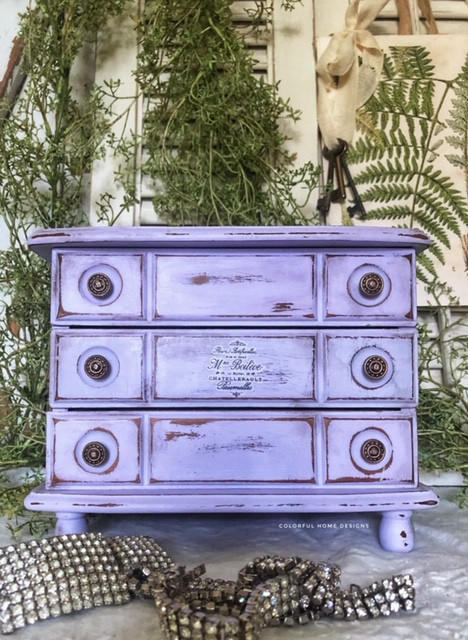Dixie Belle Paint Lucky Lavender Chalk Mineral Paint is the perfect paint for any DIY project!
Distressed dresser painted in Lucky Lavender CMP with bronze hardware. Staged with greenery around piece.