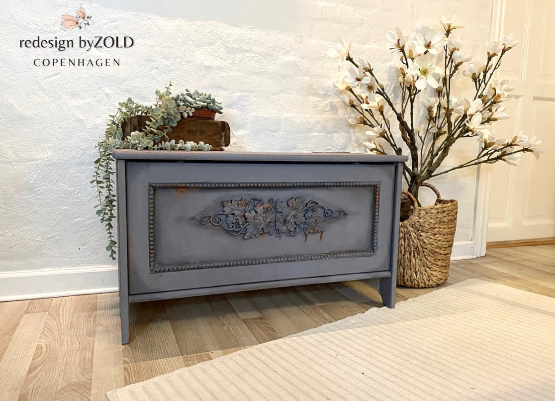 Dixie Belle Paint Manatee Gray Chalk Mineral Paint is the perfect paint for any DIY project! Chalk Painted Blanket box In a Dark Gray color. Staged with a wooden box with some trailing plants inside.